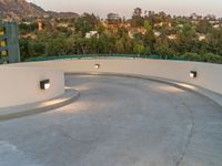 a very large circular concrete area by the trees and hill tops in the background of the city