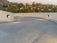 a very large circular concrete area by the trees and hill tops in the background of the city