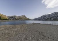 a lake in a mountain area with the water running through it's sides and mountains behind it