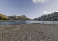 a lake in a mountain area with the water running through it's sides and mountains behind it