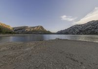 a lake in a mountain area with the water running through it's sides and mountains behind it