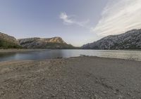 a lake in a mountain area with the water running through it's sides and mountains behind it