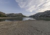 a lake in a mountain area with the water running through it's sides and mountains behind it