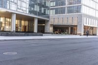 a fire hydrant in the middle of an empty city street with people walking on the sidewalk and an office building in the background