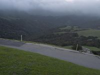 a skateboard on a hilly green slope next to trees and mountains as the sun is setting