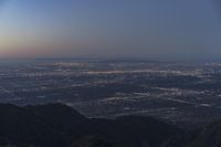 a mountaintop with the sky filled with bright lights in the background and the sun setting on top