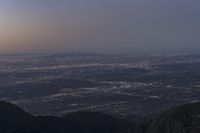 a mountaintop with the sky filled with bright lights in the background and the sun setting on top