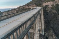 a very tall bridge that looks like it has been constructed on the mountain side by some water