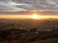 the sun is setting over the city from a hill top in the california mountains, near to the ocean