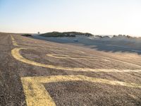 a long winding road with many markings on the ground next to a beach and sand dunes