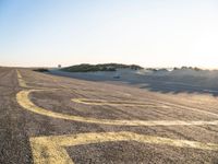 a long winding road with many markings on the ground next to a beach and sand dunes