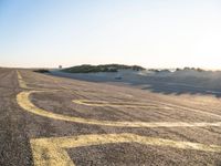 a long winding road with many markings on the ground next to a beach and sand dunes