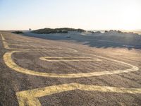 a long winding road with many markings on the ground next to a beach and sand dunes