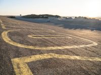 a long winding road with many markings on the ground next to a beach and sand dunes