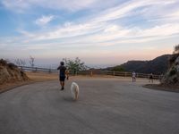 people walk along a winding path at sunset on the ocean in the distance are mountains