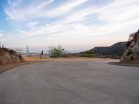 people walk along a winding path at sunset on the ocean in the distance are mountains