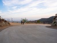 people walk along a winding path at sunset on the ocean in the distance are mountains