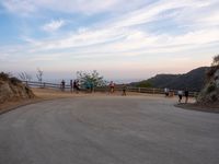 people walk along a winding path at sunset on the ocean in the distance are mountains