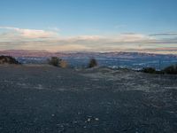 a man taking photos with his cell phone at the top of a hill looking over the city