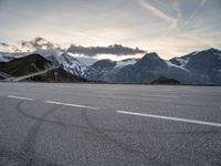 a snow covered road with mountains in the background at sunset with a white painted over line in the foreground