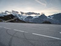 a snow covered road with mountains in the background at sunset with a white painted over line in the foreground