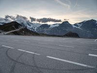 a snow covered road with mountains in the background at sunset with a white painted over line in the foreground