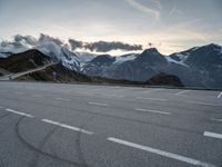 a snow covered road with mountains in the background at sunset with a white painted over line in the foreground