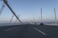 cars drive across an overpass on a bridge that is spanning across the water and mountains