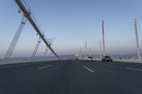 cars drive across an overpass on a bridge that is spanning across the water and mountains