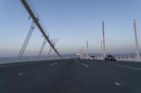 cars drive across an overpass on a bridge that is spanning across the water and mountains