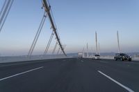 cars drive across an overpass on a bridge that is spanning across the water and mountains