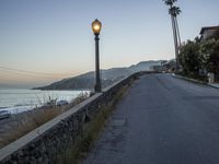 a street light next to the ocean along a cliff side road that is lined by buildings