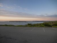 an empty parking lot next to the beach and cityscape, with a blue sky above