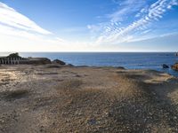 an empty beach with a few boats on it and some sand and rocks in the water