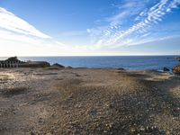 an empty beach with a few boats on it and some sand and rocks in the water