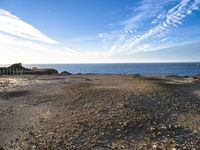 an empty beach with a few boats on it and some sand and rocks in the water