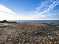 an empty beach with a few boats on it and some sand and rocks in the water