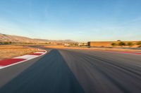 a photo of a dirt race track with sun setting in the distance of the track