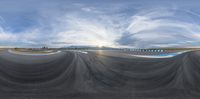 a camera lens is reflecting the sky over a runway where a red car and a motorcycle are driving along