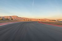 a photo of a dirt race track with sun setting in the distance of the track