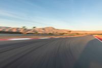 a photo of a dirt race track with sun setting in the distance of the track