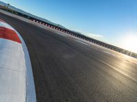 a photo of a dirt race track with sun setting in the distance of the track