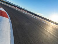 a photo of a dirt race track with sun setting in the distance of the track