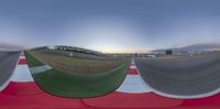 a panoramic view of the racetrack with an airplane flying in the background and another person standing on the run way