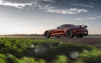 a red sports car driving down an empty road with blurry grass in the foreground