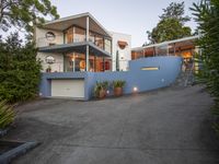 a driveway leading up to a house with stairs to the upper level on one level, a deck and terraced area on the other side