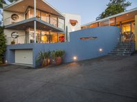 a driveway leading up to a house with stairs to the upper level on one level, a deck and terraced area on the other side