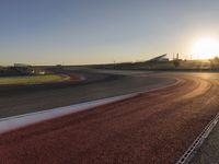 an image of a racetrack with a sunset in the background and a line of red