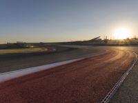 an image of a racetrack with a sunset in the background and a line of red