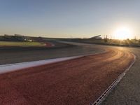 an image of a racetrack with a sunset in the background and a line of red